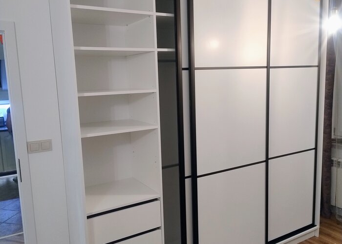 Biała szafa wnękowa — wnętrze z półkami i drzwi przesuwne