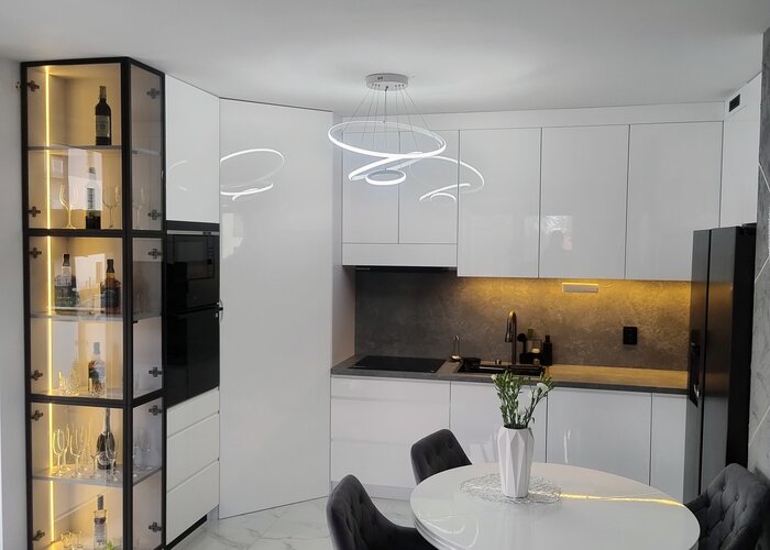 Biała kuchnia z wiszącą witryną szklaną i designerską lampą LED